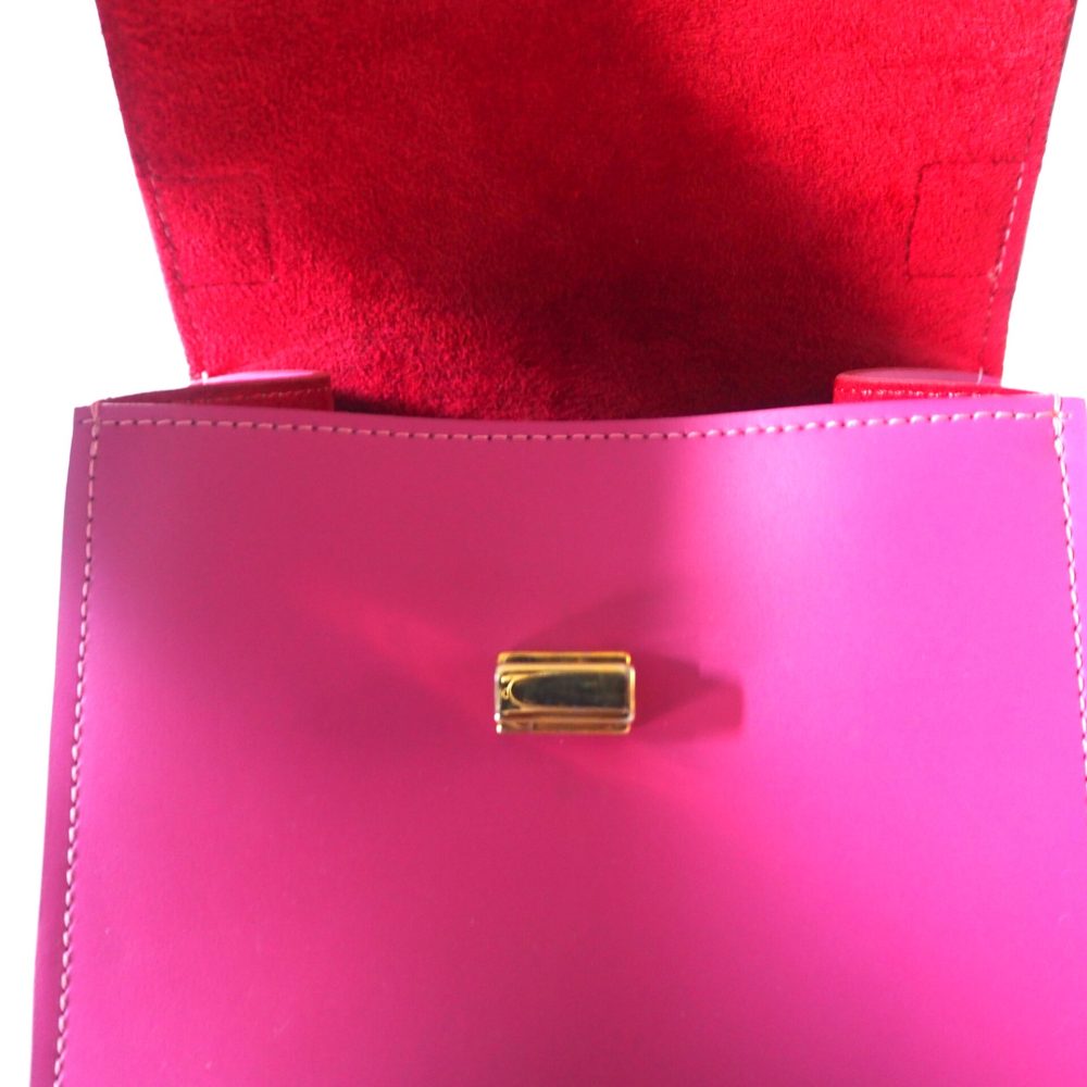 Inner view of a berry pink small designer bag with an inner red lining