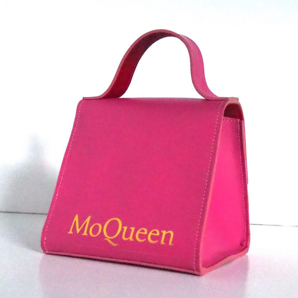 Backview of a berry pink small designer bag with an inner red lining