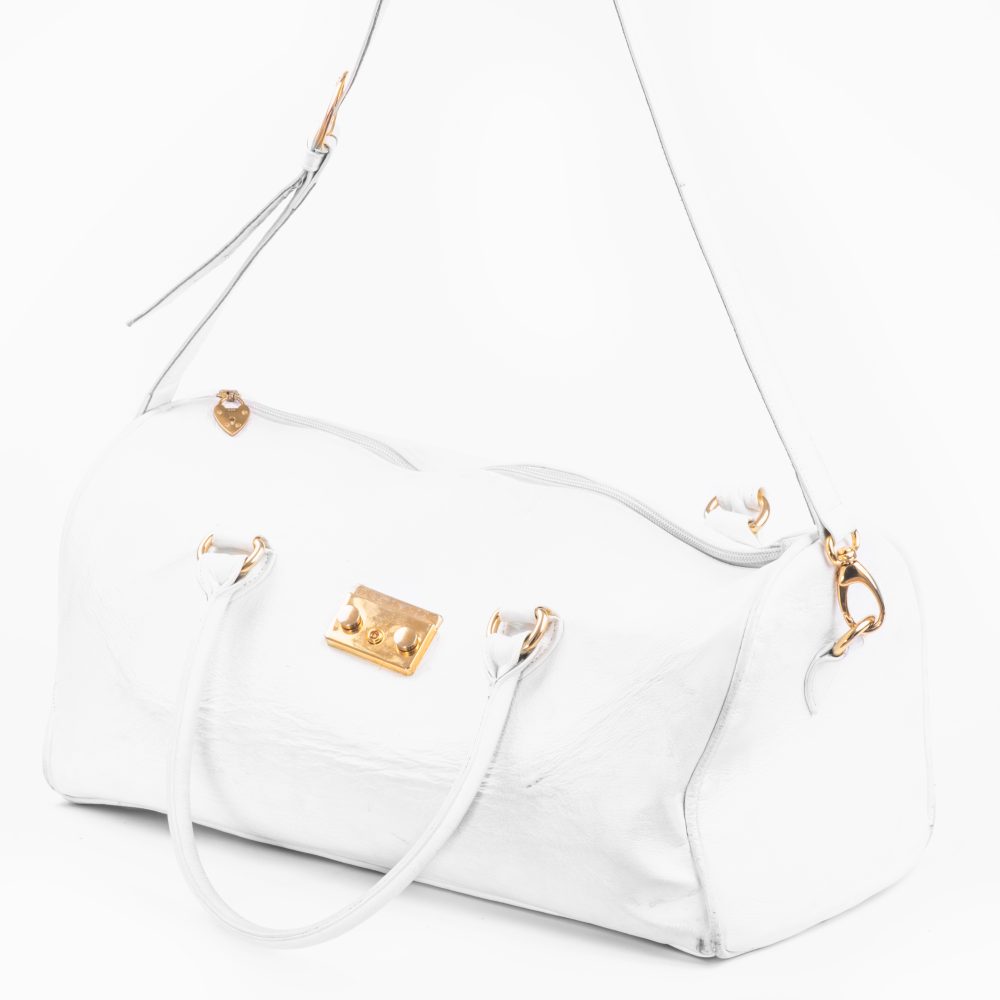 The side view of a large designer white duffle bag with the strap showing
